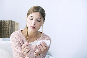 woman looking at birth control pills