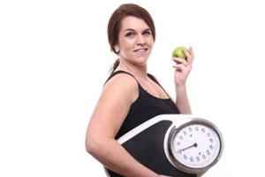 women holding weight machine and eating apple