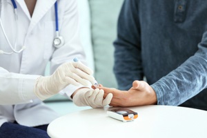 doctor taking sample of diabetic patient blood using lancet pen