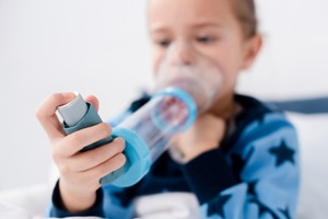 An asthmatic kid using inhaler with spacer at home