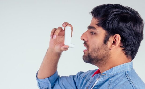 man inhaling with asthma pump