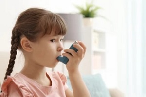 small girl inhaling asthma inhaler