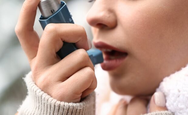 woman with inhaler having asthma attack outdoors
