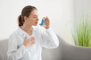 A woman using an inhaler during asthma trigger