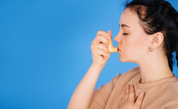 brunette girl uses an inhaler to treat asthma