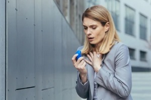 women taking inhaler after asthma attack