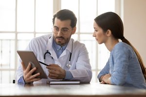 A doctor showing list of things that should be included in a asthma action plan to the female patient