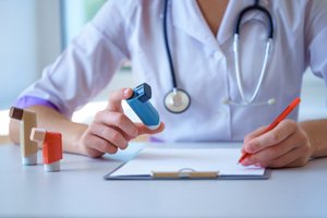 A female doctor reviewing asthma management plan while holding inhaler and stethoscope