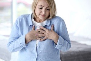 A woman pressing her hands to the chest showing pain