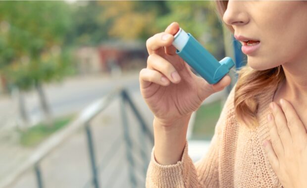 A woman using inhaler to help herself breathe