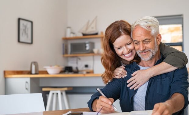 An old man preparing an asthma management action plan while his wife hugging him from back