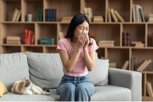 A woman allergic to a cat is sneezing