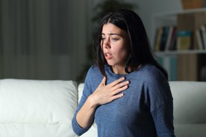 A woman experiencing shortness of breath, a sign of an asthma attack