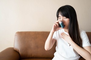 A woman is using an inhaler to stop asthma trigger