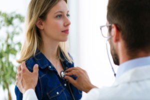 A male doctor is checking the heartbeats of a young female patient