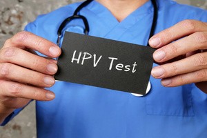 A doctor holding a blackboard that reads HPV test