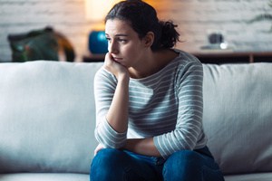 A young woman in a state of confusion while sitting on a couch