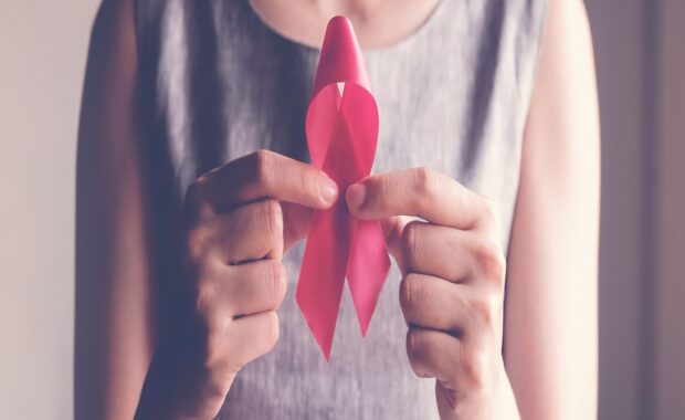 A woman holding a cancer awareness ribbon