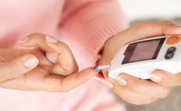 close up of woman hands checking blood sugar level by glucose meter
