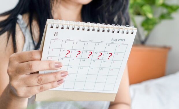 woman hand holding calendar with question mark waiting for late blood period