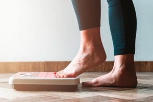 women stepping on weight scale