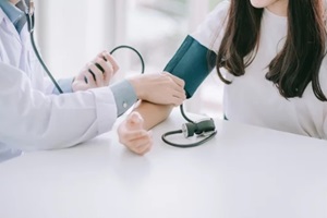 Durham, NC primary care doctor using sphygmomanometer with stethoscope checking blood pressure to a patient in the hospital