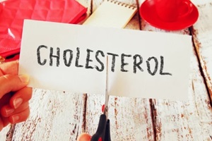 woman hands cutting card with the word cholesterol 