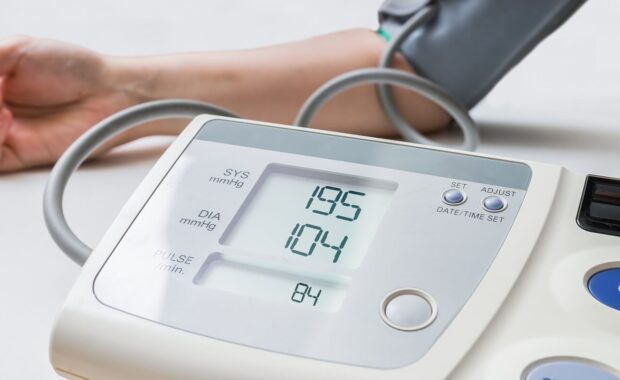 woman with hypertension measuring blood pressure with digital monitor