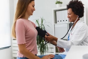 female african american doctor measuring blood pressure of a young woman