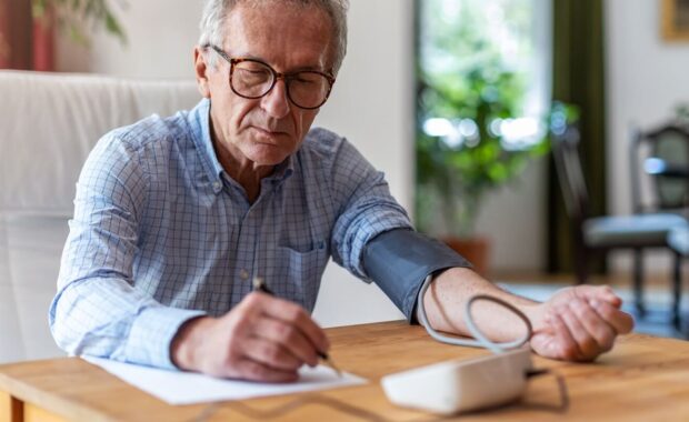 senior man using medical device to measure blood pressure