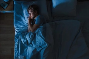 view of handsome young man sleeping cozily on a bed in his bedroom at night