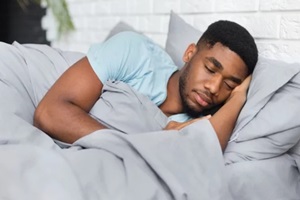 young african-american man sleeping in bed at home