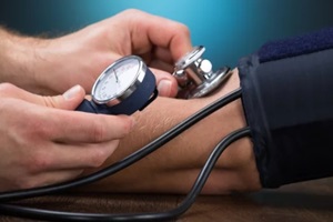 NC family doctor checking blood pressure of patient at table