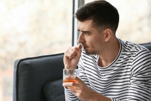 depressed young man drinking alcohol at home