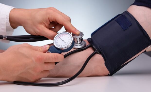 Primary care doctor checking male patient arterial blood pressure