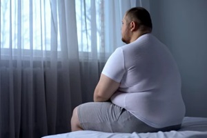 obese man sitting alone in the bed