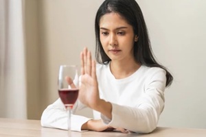 depressed asian young woman hand refuse red wine or alcoholic beverage