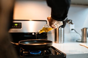 Person Pouring Cooking Oil in Pan
