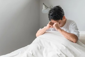 person rubbing eyes after waking up