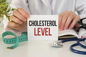 doctor holding cholesterol level card at desk with stethoscope and measuring tape