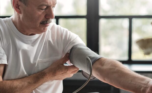 hispanic man feeling bad using a home blood pressure management machine to check his health in the morning in Durham, NC