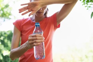 young woman drinking water in the heat of the day