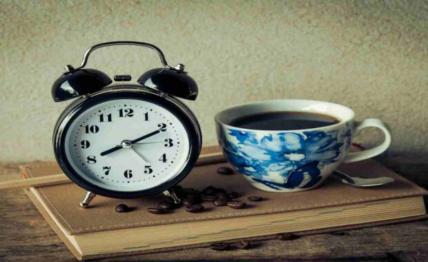 Alarm Clock with Coffee Cup and Beans Over a Book