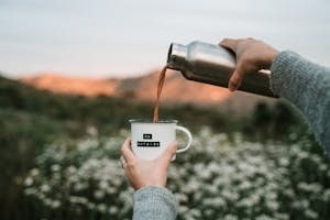 Person Pouring Coffee into Cup from Bottle