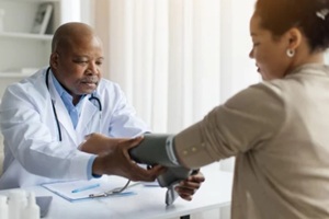 doctor man checking blood pressure to female patient with upper arm monitor