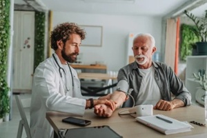 doctor measuring blood pressure of senior patient in medical clinic