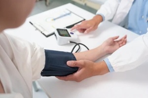 doctor using a digital sphygmomanometer, measuring blood pressure of a patient during a medical examination in the hospital