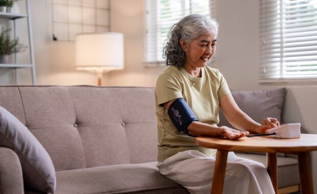 older woman independently monitors blood pressure at home for proactive health management and personal wellness