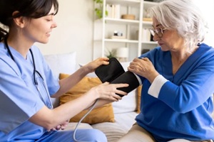 nurse measuring blood pressure of senior woman at home