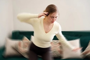 woman gets dizzy, loses her balance in the living room